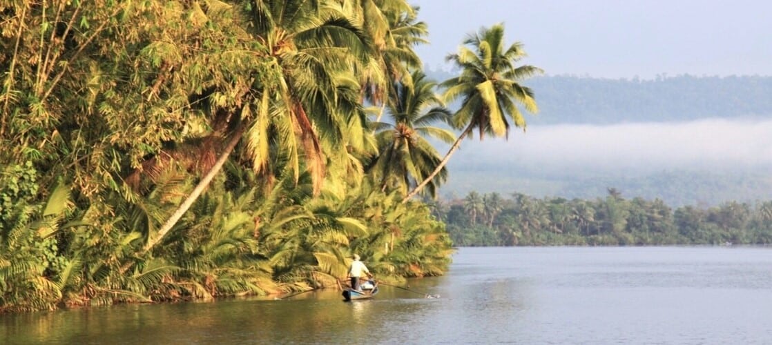 Scène de vie où pêcheur navigue sur la rivière qui traverse la jungle des montagnes des Cardamomes